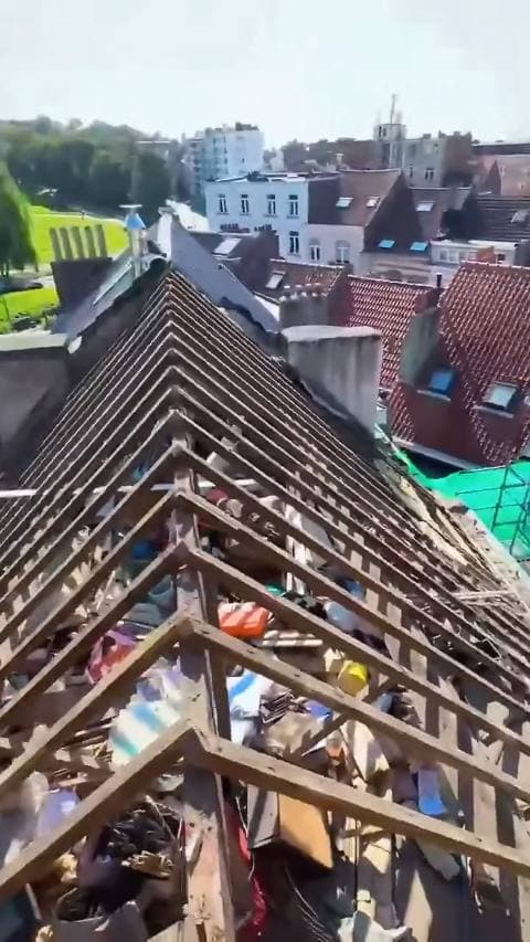 Een gestript dak met blote kepers, van bovenaf gezien met de stad erachter
